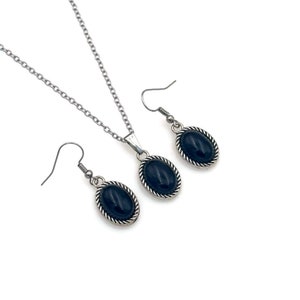 May include: A silver necklace and earrings set with black oval stones. The stones are set in a silver bezel with a rope-like design.