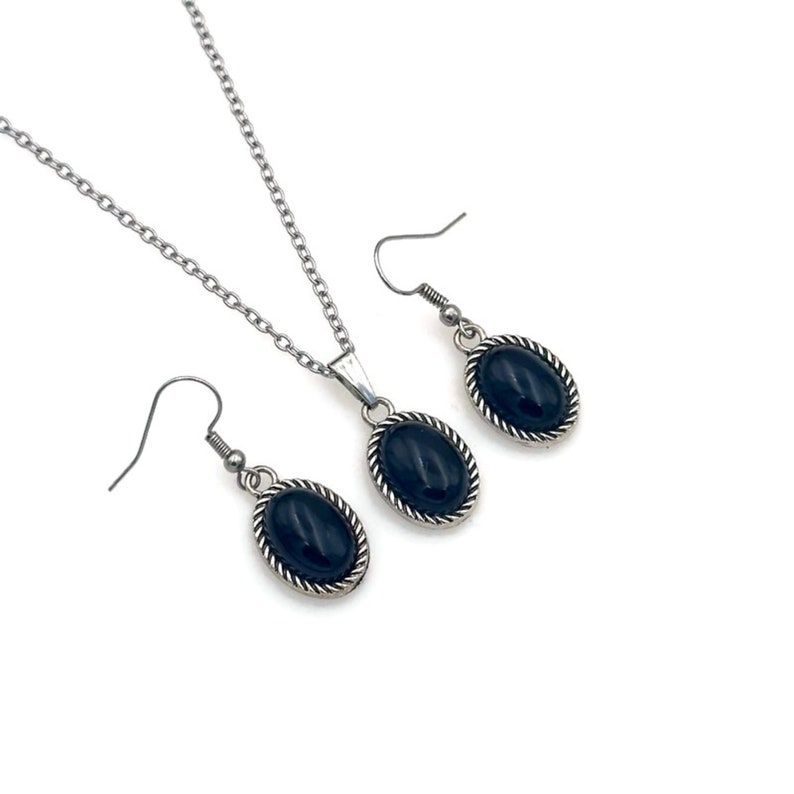 May include: A silver necklace and earrings set with black oval stones. The stones are set in a silver bezel with a rope-like design.