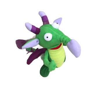May include: Green plush dragon toy with purple wings and horns. The dragon has large white eyes and a yellow belly.