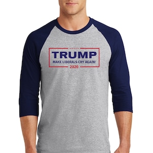 Puede incluir: Una camiseta de béisbol gris y azul marino con un gráfico rojo y azul que dice "TRUMP MAKE LIBERALS CRY AGAIN! 2020".