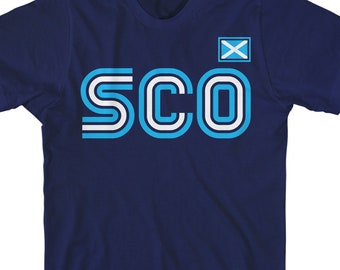 May include: A navy blue t-shirt with a white and blue striped design that says "SCO" with a small Scottish flag in the top right corner.