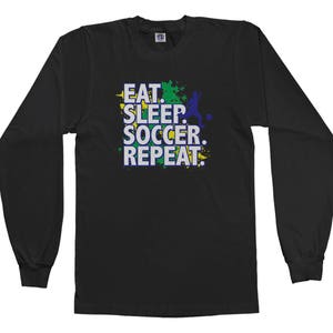 May include: Black long-sleeved t-shirt with a green, yellow and blue graphic print that says "Eat. Sleep. Soccer. Repeat."