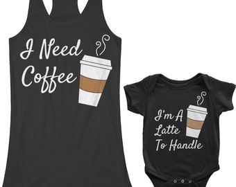 Könnte beinhalten: Ein schwarzes Tanktop mit dem Text "I Need Coffee" und einer Comic-Kaffeetasse. Ein schwarzer Baby-Strampler mit dem Text "I'm A Latte To Handle" und einer Comic-Kaffeetasse.