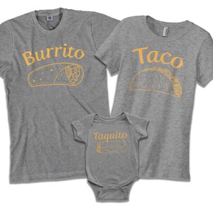 May include: A set of three gray t-shirts with a burrito, taco, and taquito design. The shirts have the words "Burrito", "Taco", and "Taquito" printed on them in orange.