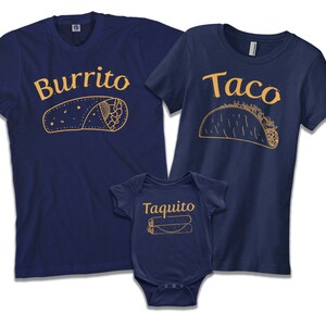 May include: A set of three navy blue t-shirts with a burrito, taco, and taquito design. The shirts have the words "Burrito", "Taco", and "Taquito" printed on them in a gold color.