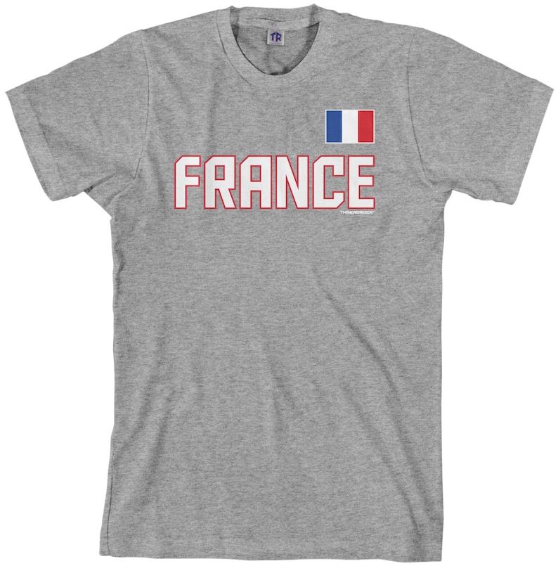 May include: A gray t-shirt with the word "FRANCE" in red with a white outline and a small French flag in the upper right corner.