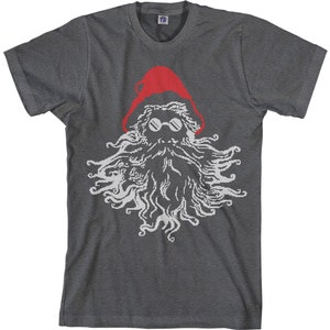 May include: A dark gray t-shirt with a white and red graphic of a Santa Claus with sunglasses. The Santa Claus is wearing a red hat and has a long white beard.