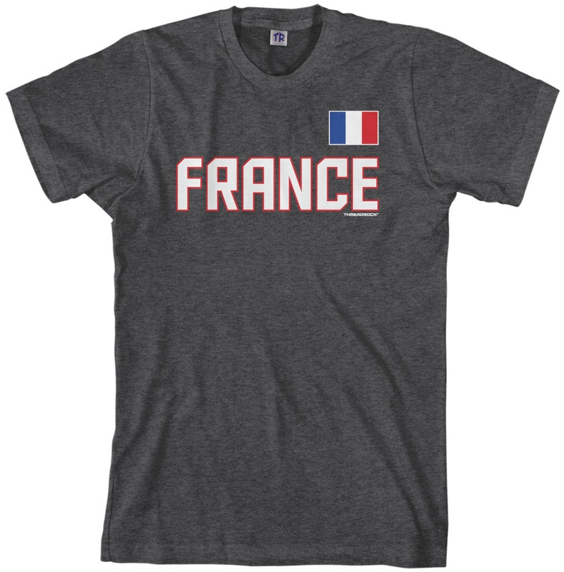 May include: A dark heather grey t-shirt with a white graphic of the word "FRANCE" in bold red letters. A small French flag is displayed above the word.