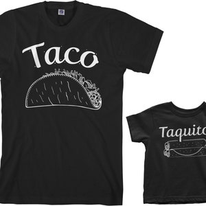 May include: Black t-shirts with white text and images. The larger shirt says "Taco" with a drawing of a taco. The smaller shirt says "Taquito" with a drawing of three taquitos.