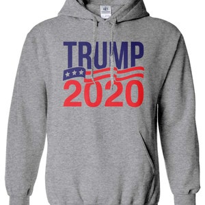 May include: Grey hooded sweatshirt with the text "TRUMP 2020" in red and blue lettering. The text is overlaid with a stylised American flag design.