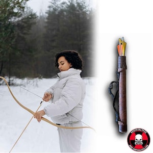 May include: A person in a white jacket is holding a wooden bow and arrow. The arrow is in the quiver, which is a brown leather tube with a strap. The quiver is hanging on a white background.