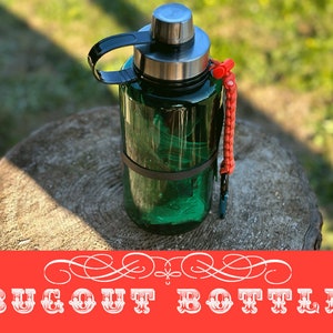 May include: A green water bottle with a black handle and a silver lid. The bottle has a black band around it and a red lanyard attached to the lid. The bottle is sitting on a wooden stump. The text "BUGOUT BOTTLE" is written in white letters on a red background.