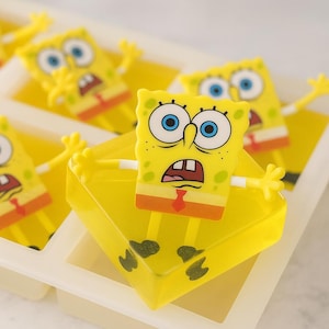 May include: Yellow SpongeBob SquarePants ice cube tray with multiple character figures. Each figure has blue eyes, a red tie, and orange shorts. The tray is made of yellow plastic.