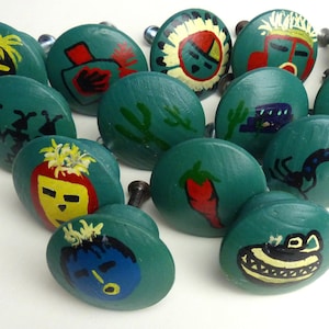 May include: A set of 13 teal green painted wooden knobs with various designs, including Native American inspired patterns, animals, and plants.