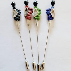 May include: Four silver dragon pins with black, red, green, and blue dragons. Each pin has a black bead at the top and a silver pin back.