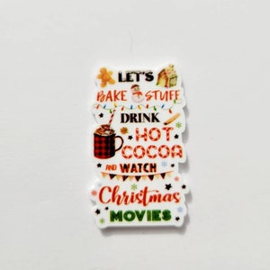 May include: A white ceramic ornament with a Christmas-themed design. It features a red and black mug with a red and white striped straw, a gingerbread man, a snowman, a house, and the text "Let's bake stuff, drink hot cocoa and watch Christmas movies".