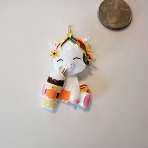 May include: A white unicorn figurine with a colorful mane, flower crown, and a pumpkin spice latte. The unicorn is holding the latte and has a happy expression. The figurine is approximately 1.5 inches tall.