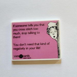 May include: A rectangular magnet with a pink background and white border. The text reads: "If someone tells you that you cross stitch too much, stop talking to them! You don't need that kind of negativity in your life!" A cartoon woman peeks from the right.
