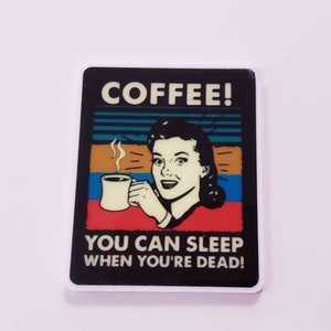 May include: A retro-style illustration of a woman holding a cup of coffee with the text "COFFEE! YOU CAN SLEEP WHEN YOU'RE DEAD!"