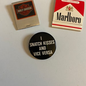 May include: An assortment of vintage items including a matchbook with the Harley-Davidson Cycles logo, a pack of Marlboro cigarettes, and a black button with the text "I SNATCH KISSES AND VICE VERSA."