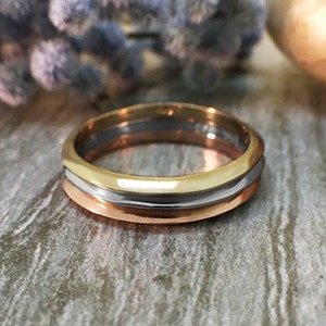 May include: A gold, silver, and rose gold wedding band with a smooth, polished finish.