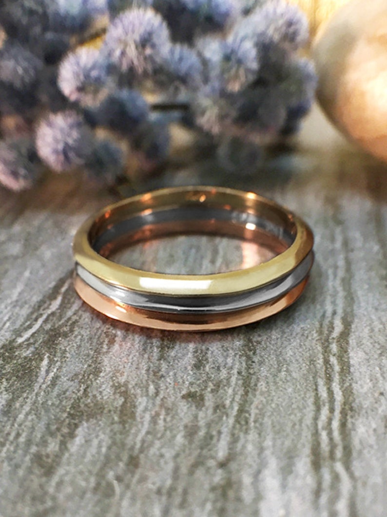 May include: A gold, silver, and rose gold wedding band with a smooth, polished finish.