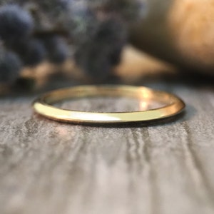 May include: A simple, thin gold band ring. The ring is smooth and polished.