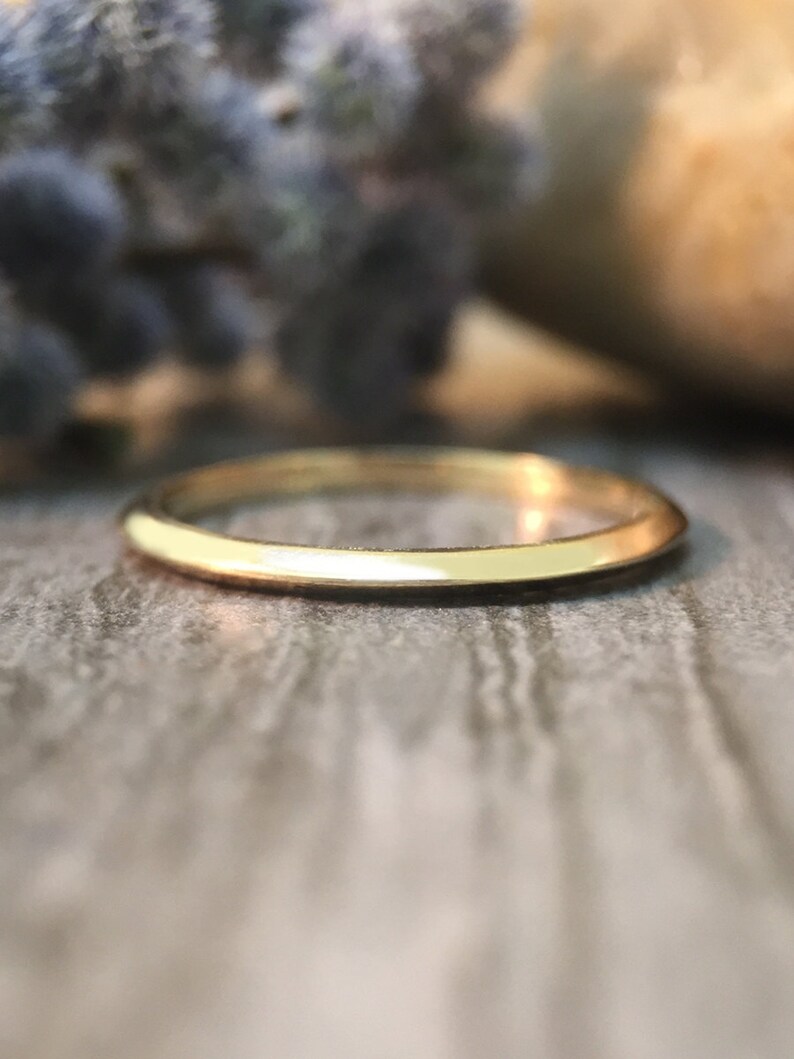 May include: A simple, thin gold band ring. The ring is smooth and polished.