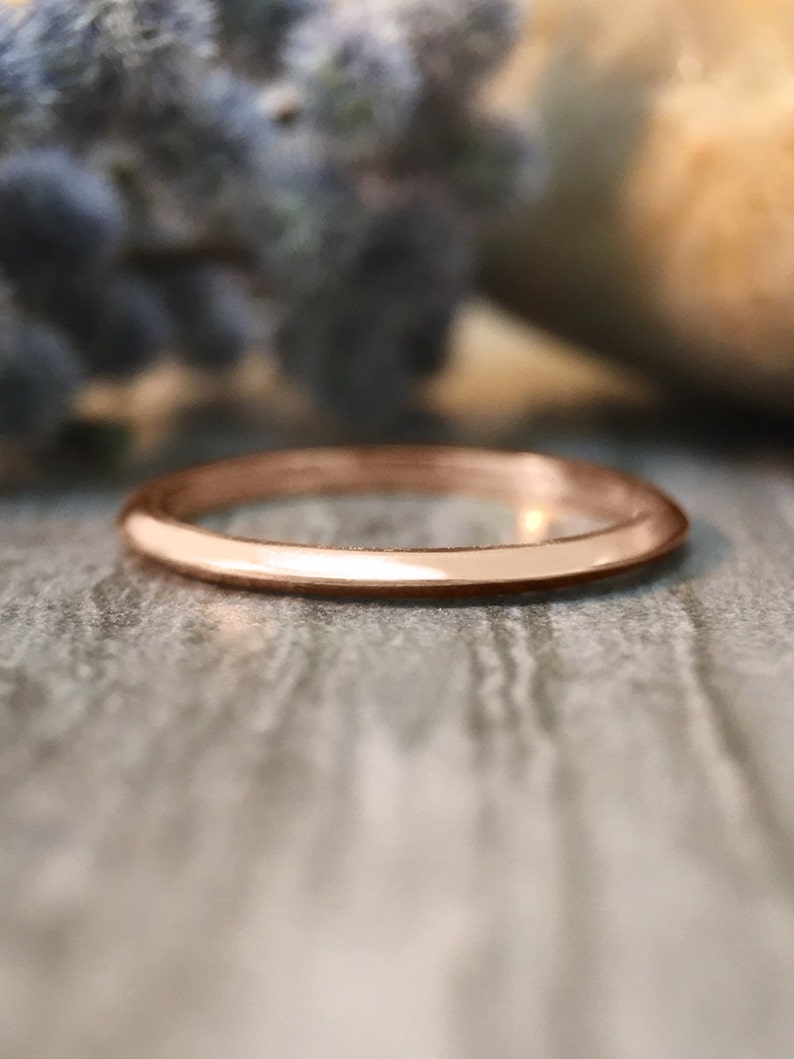 May include: A simple, polished, rose gold band ring.