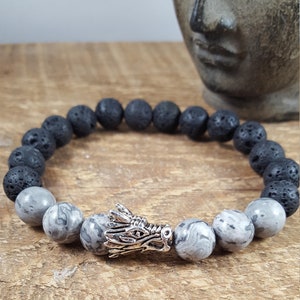 May include: A black lava rock and grey marbled stone bracelet with a silver dragon head charm.