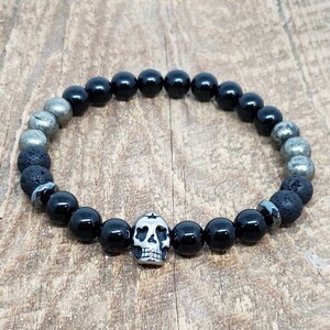 May include: Black onyx and pyrite beaded bracelet with a silver skull charm.