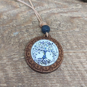 May include: A wooden pendant necklace with a brown cord and a round wooden charm featuring a blue and white tree of life design.
