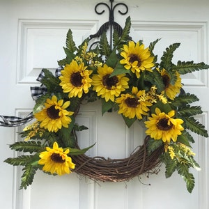 Pu&ograve; includere: Una ghirlanda di girasoli con nastro a quadri bianco e nero. La ghirlanda &egrave; realizzata in vite e presenta girasoli e verde artificiali.