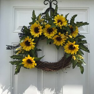 Pu&ograve; includere: Una ghirlanda di girasoli con una base di vite marrone. La ghirlanda &egrave; decorata con girasoli gialli e foglie verdi.