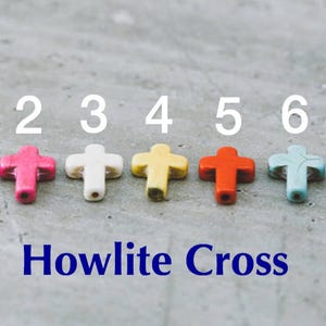 May include: Seven Howlite cross beads in different colors, numbered 1 through 7. The beads are red, pink, white, yellow, orange, blue, and black.