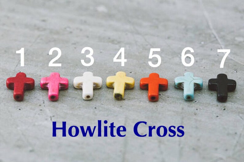 May include: Seven Howlite cross beads in different colors, numbered 1 through 7. The beads are red, pink, white, yellow, orange, blue, and black.