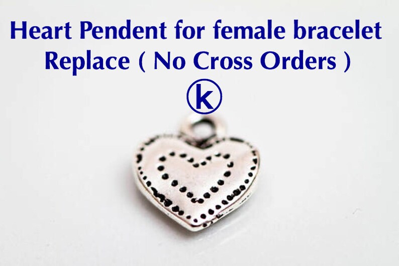 May include: Silver heart charm with a dotted design. The charm has a loop at the top for attaching to a bracelet or necklace. The charm is labeled with the letter "K".