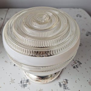 May include: A vintage clear glass light fitting with a white band and a silver base. The glass dome features a spiral design and ribbed detailing. The fitting is likely for a ceiling or wall mount, adding a classic touch to any room.