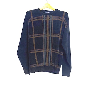 May include: A navy blue sweater with a plaid pattern in shades of brown, blue, and gray. The sweater has a crew neck and long sleeves. The garment is hanging on a wooden hanger.