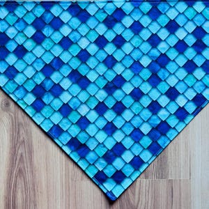 May include: A triangular bandana featuring a repeating pattern of diamond-shaped scales in various shades of blue, ranging from light cyan to deep navy. The fabric has a consistent geometric texture across the entire surface of the accessory.