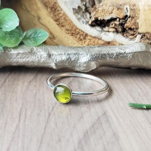 Op de afbeelding: Een zilveren ring met een groene edelsteen in het midden.