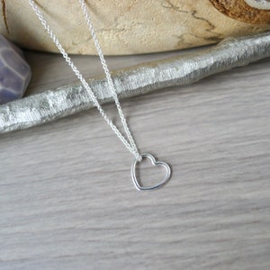 May include: A silver chain necklace with a delicate open heart pendant.