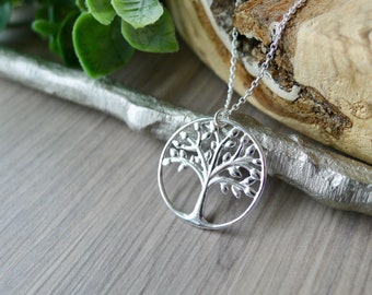 Puede incluir: Un collar de plata con un colgante de árbol de la vida. El colgante es un círculo con un diseño de árbol detallado.