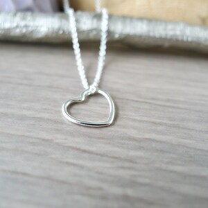 May include: A silver necklace with a delicate open heart pendant.