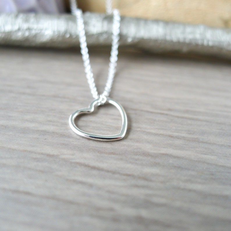 May include: A silver necklace with a delicate open heart pendant.