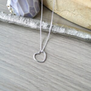 May include: A silver chain necklace with a delicate open heart pendant.