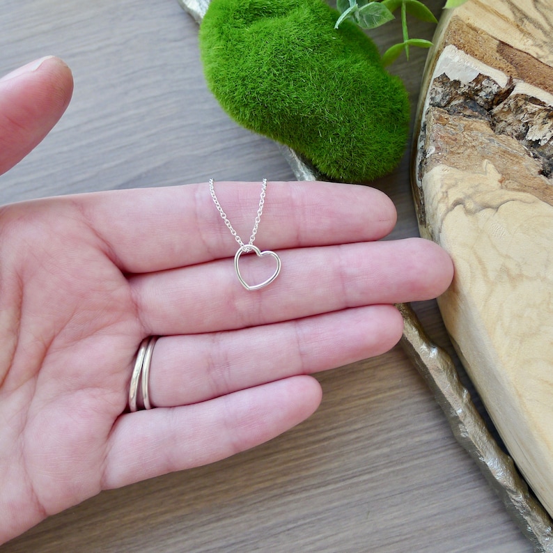 May include: A delicate silver necklace with a simple open heart pendant.