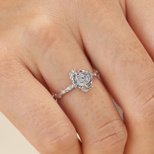 May include: A silver ring with a delicate rose design. The rose is made of intricate wirework and has a small clear stone in the center.