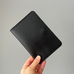 May include: A black leather wallet with a stitched edge.
