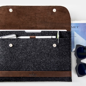 Leather and Felt laptop case open with Apple pencil in the loop. The case has CITYSHEEP logo embossed. Sunglases close to the csae.